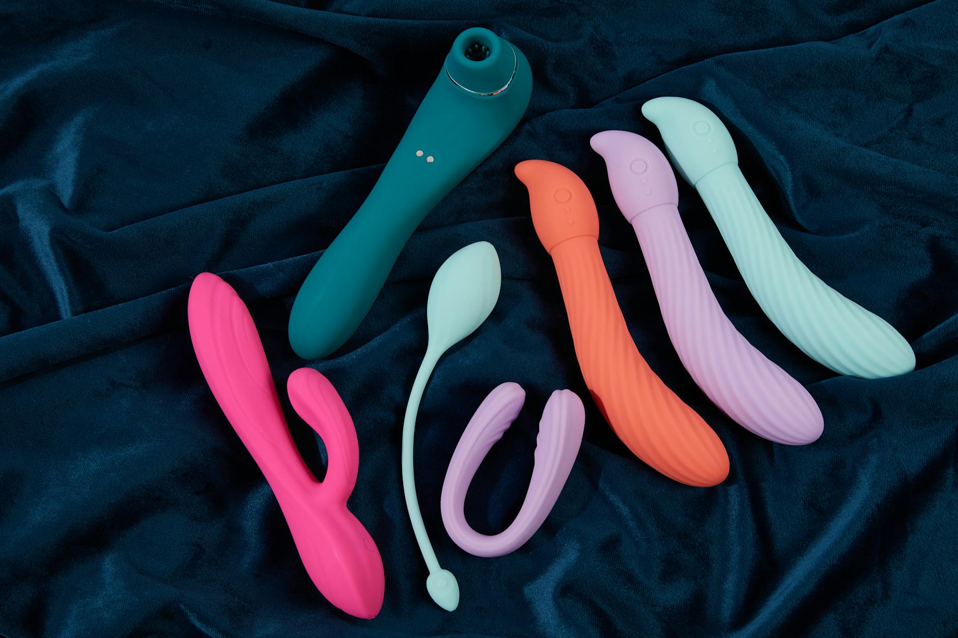 Collection of colorful silicone vibrators displayed on textured fabric