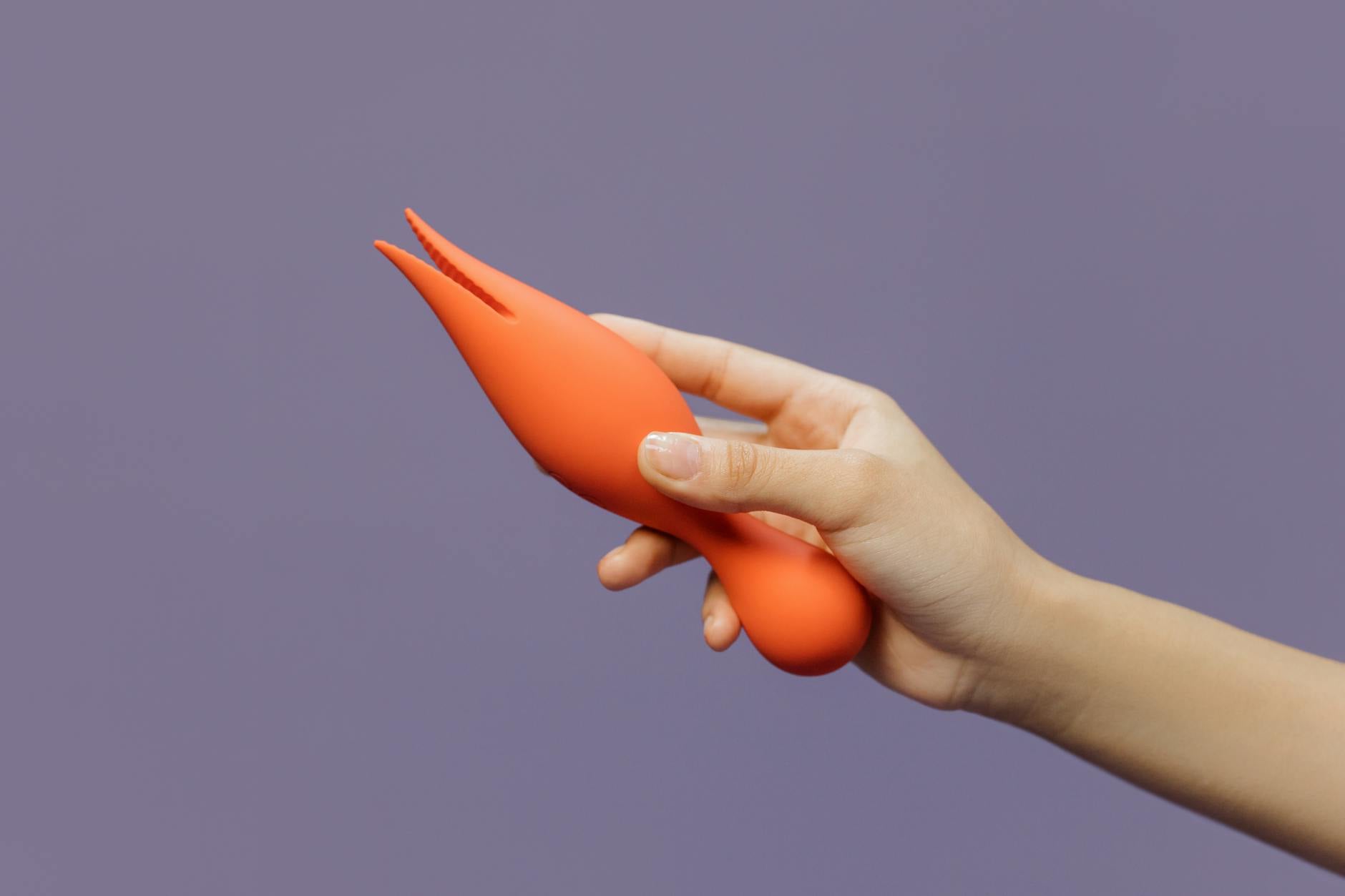 Hand holding a lemon-colored vibrator against a purple backdrop, ready for comfortable exploration.