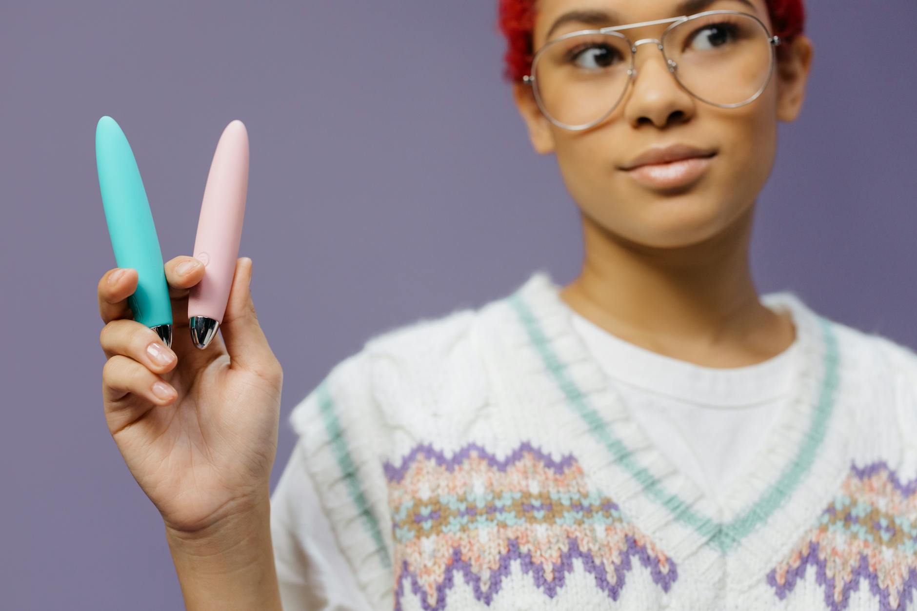 Woman holding colorful silicone toys against a purple background, representing choices in pleasure recovery