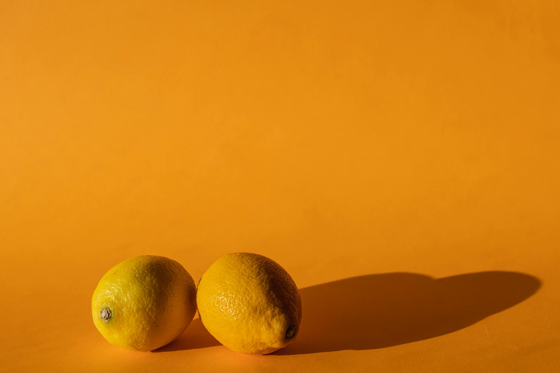 Hand holding a fresh lemon on soft pink background, symbolizing gentle, sensitive care